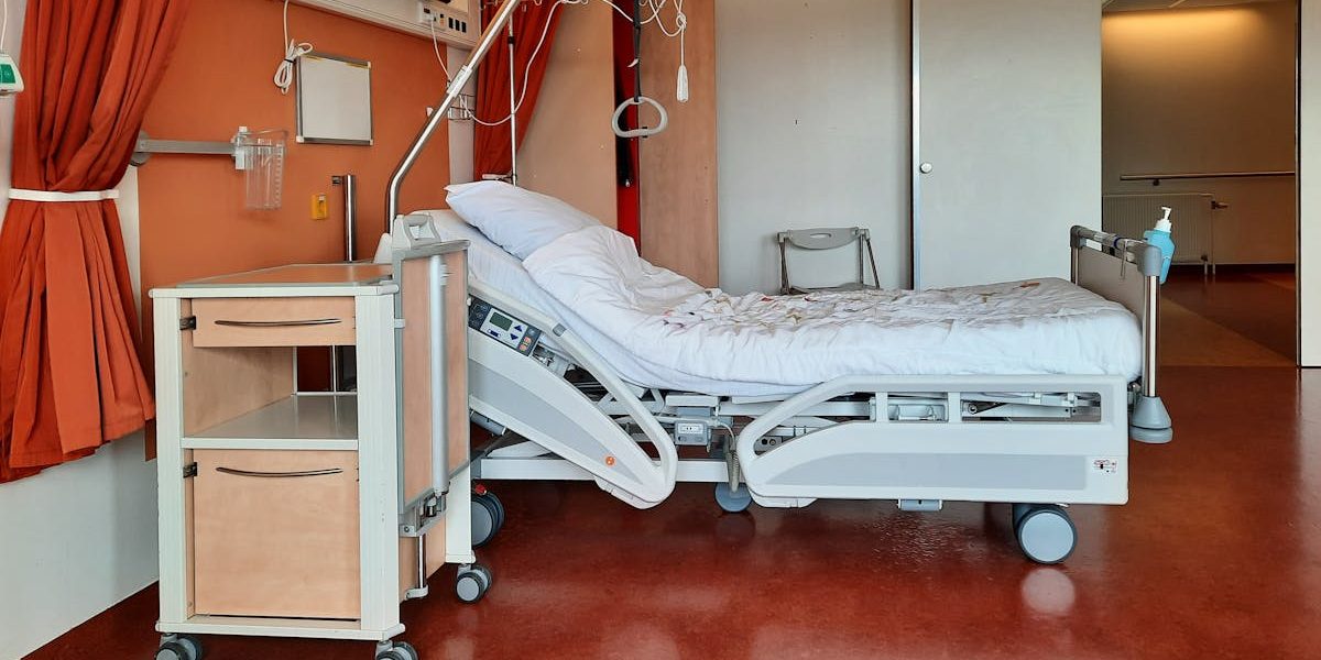 A clean and modern hospital room equipped with an adjustable bed and medical equipment.