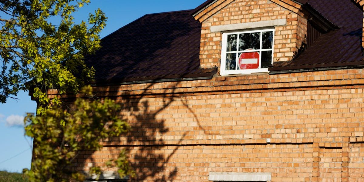 Close-up of a red brick house exterior featuring a no entry sign in a window.