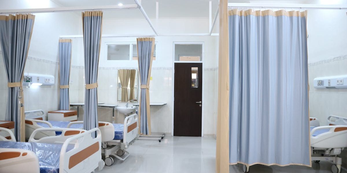 Spacious hospital ward in Surabaya, Indonesia with multiple medical beds and privacy curtains.