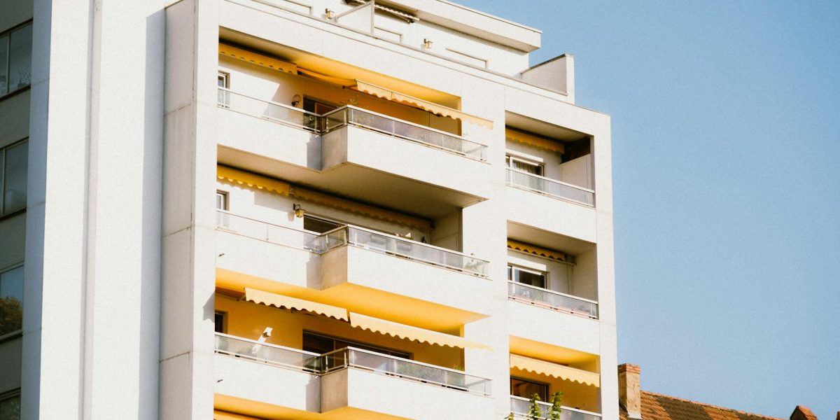 Low-angle view of a contemporary apartment building with yellow balconies against a clear sky.